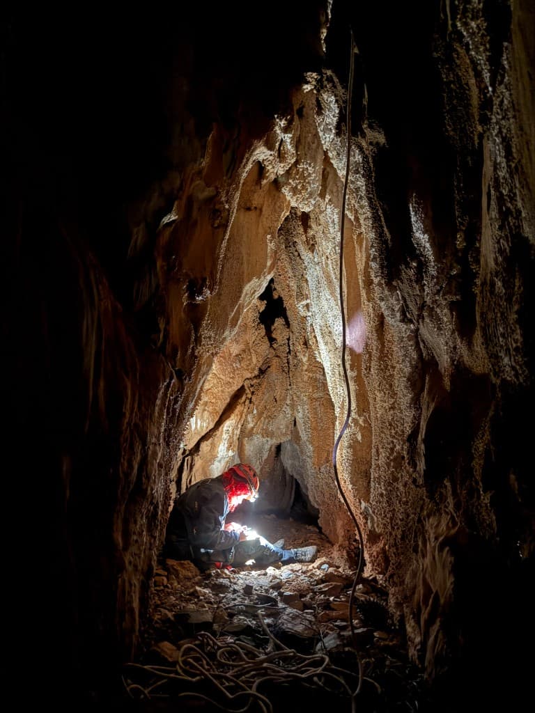 Caving in a narrow passage with headlamp